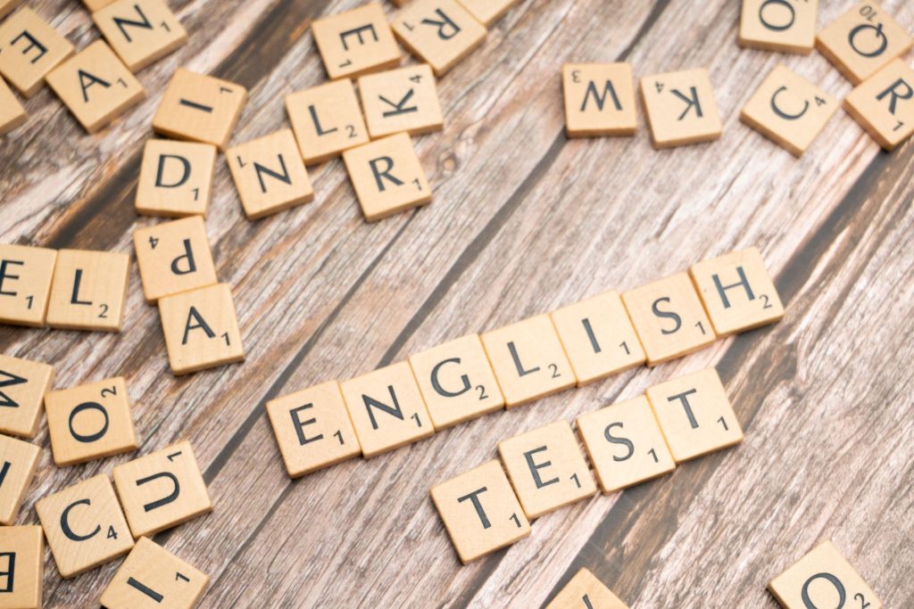 Des lettres en bois de Scrabble épelant 'Test d'anglais' sur un fond en bois, idéal pour des thèmes d'examen de langue.