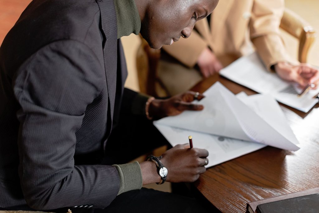 Homme afro-américain concentré sur la signature de documents d'affaires importants à un bureau.