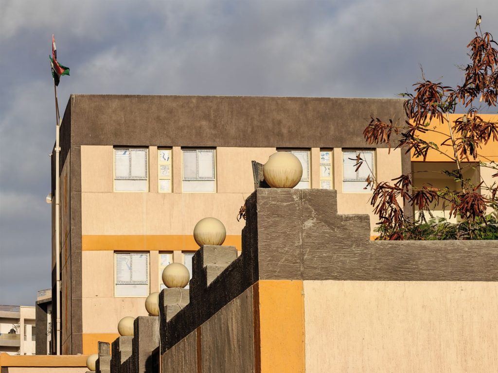 Photo d'un bâtiment rectangulaire moderne avec un drapeau contre un ciel nuageux.