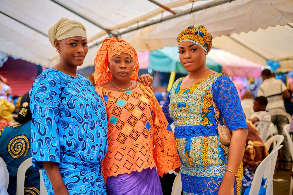 Trois femmes en vêtements africains traditionnels lors d'un événement culturel dynamique à Abidjan.