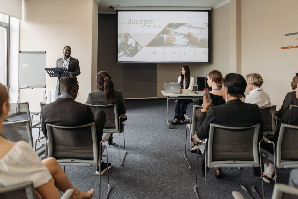 Un groupe divers d'adultes assistent à une présentation dans un cadre de salle de conférence.