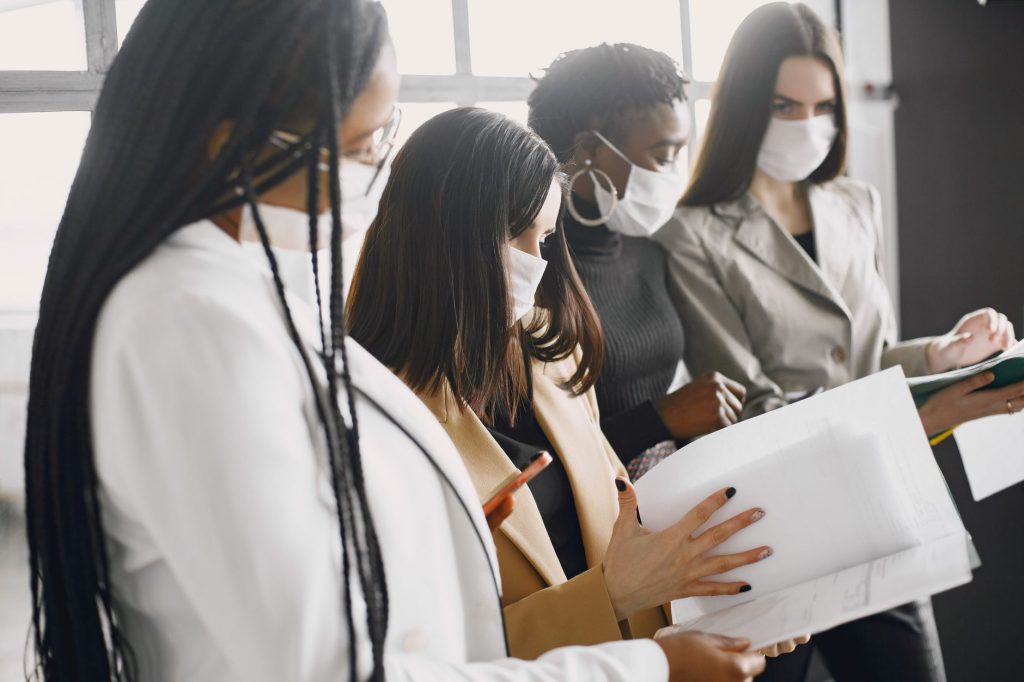 Un groupe diversifié de femmes travaille ensemble dans un bureau, illustrant le travail d'équipe et la collaboration.