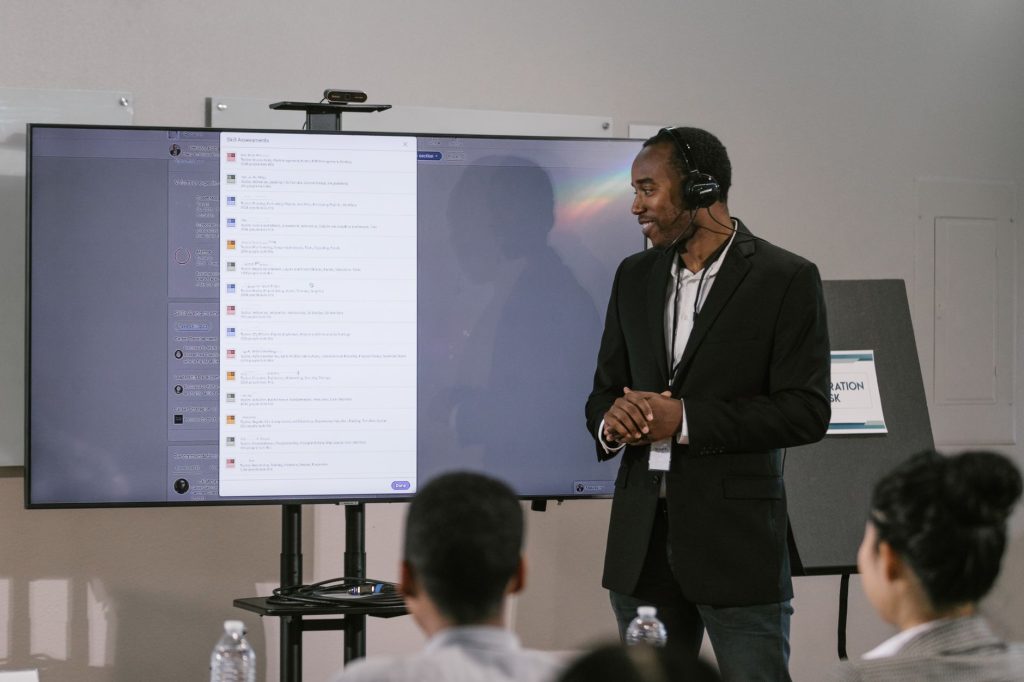Un homme adulte présente lors d'un séminaire technologique en utilisant un grand écran et un casque.
